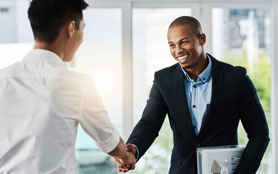 An IT administrator shaking hands with an office manager
