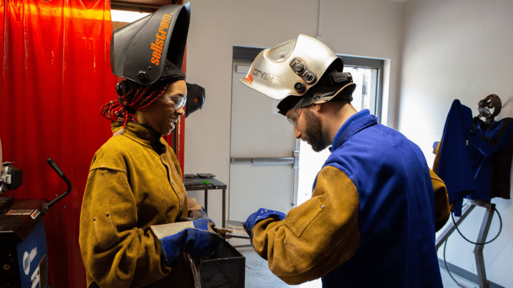 a black female Centura College student having her white male instructor review the weld she did  while implementing practices to prevent Welding Fires