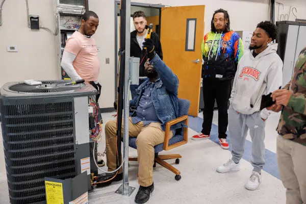 HVAC instructor sitting in a chair with students around him