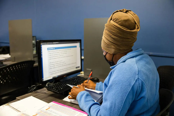 An allied health management graduate sitting at a desk working on a computer