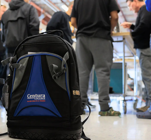 A Centura College branded backpack with students working in the background