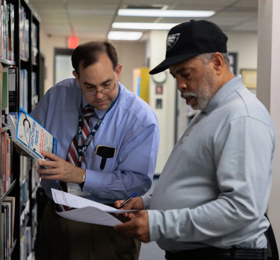 Two Centura College staff members in the school library reviewing books