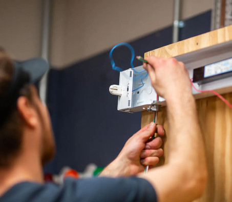 A Centura College electrician program student working on a light fixture