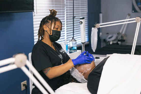 An esthetician student practicing a facial treatment on another student