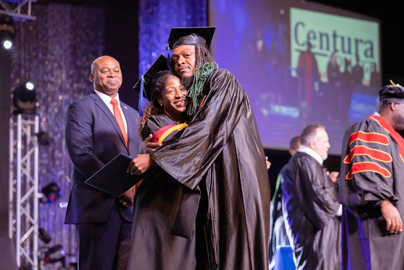 Two Centura College graduates hugging on stage during graduation