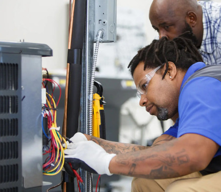 A Centura College HVAC student working on a practice AC unit