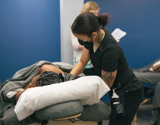 A massage therapy student practicing massage on another student