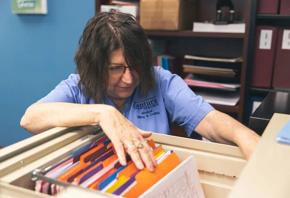 A medical billing and coding student checking files in a file cabinet