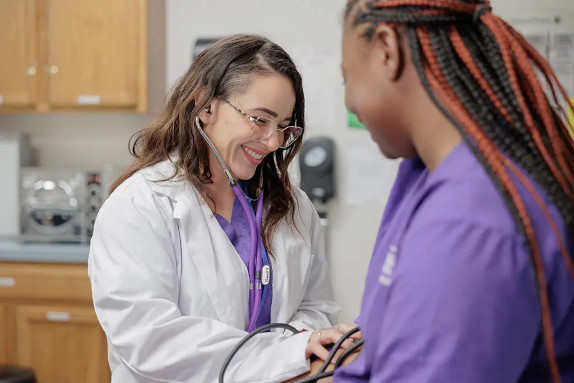 A medical assistant student practicing taking blood pressure on another student