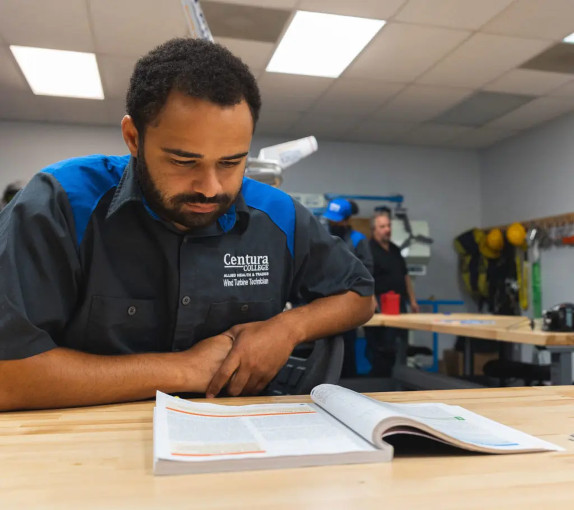 A wind turbine program student sitting at a desk reading a textbook