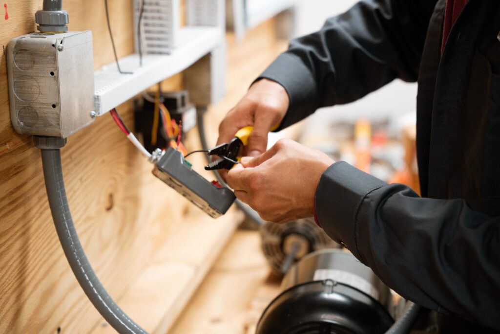 A student in a vocational training lab works on wiring and electrical components, gaining hands-on experience that fulfills prerequisites for electrician certification