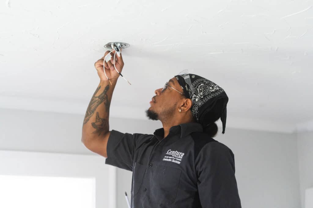 A Centura College Construction Electrician student works on ceiling wiring, gaining hands-on skills that meet electrician apprenticeship prerequisites.