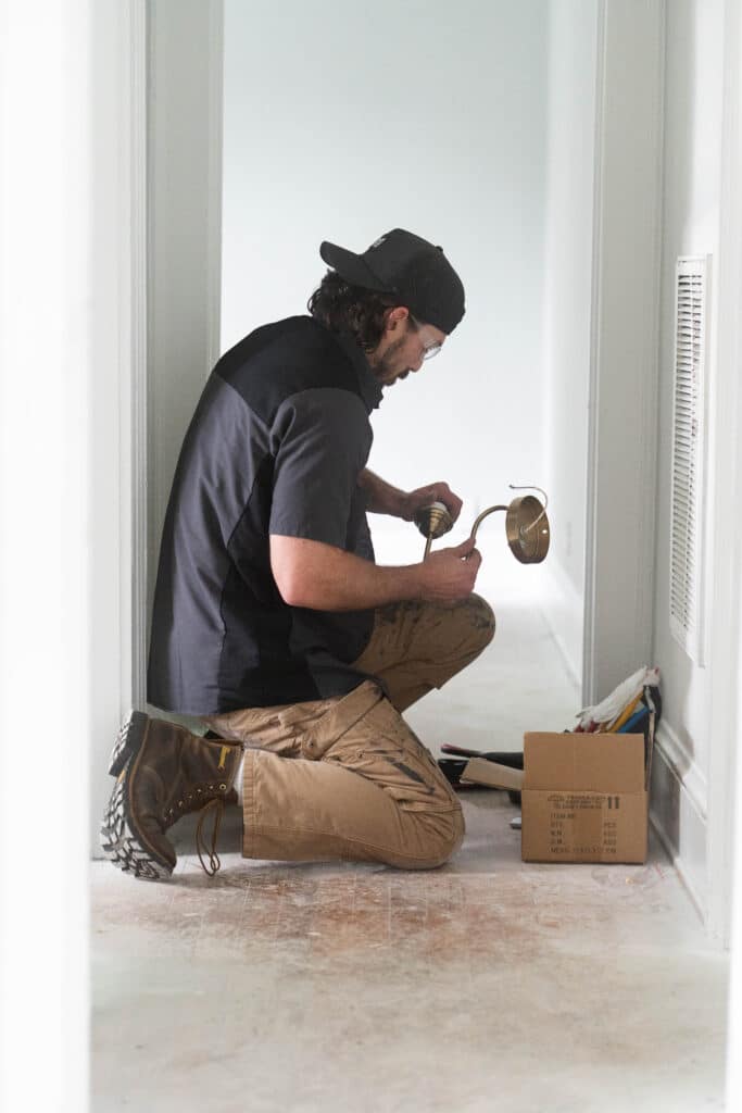 A student in the electrician apprentice program at Centura College installs a light fixture during hands-on training.